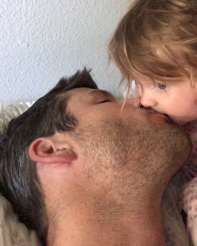 A picture of Parker Young kissing his daughter.